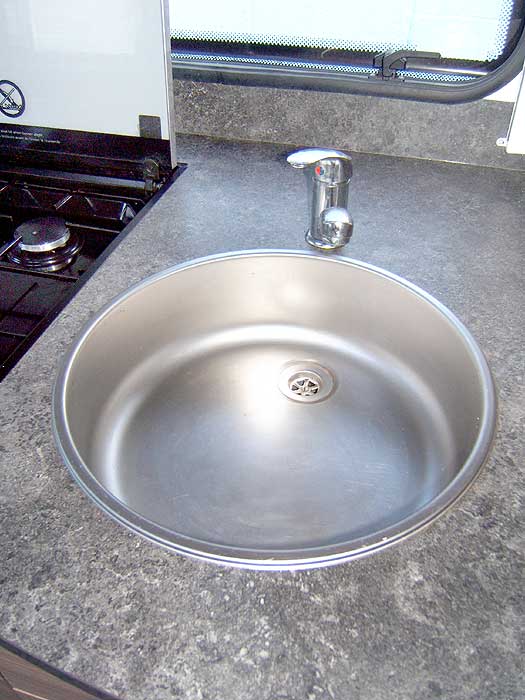 The stainless steel kitchen sink with mixer tap.